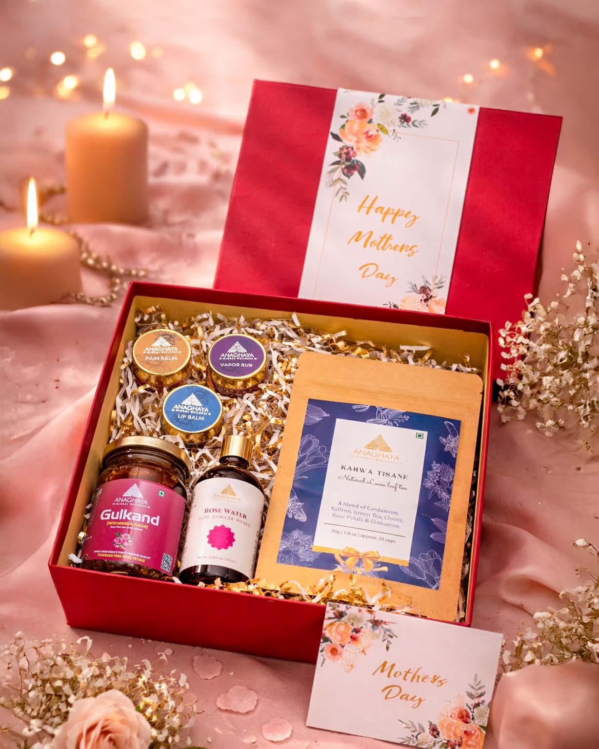 Open gift hamper showing rose water, gulkand, kahwa tea, pain relief balm, vapour rub, and lip balm arranged neatly with decorative fillers.